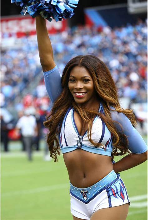 a cheerleader at a football game holding her pom poms in the air