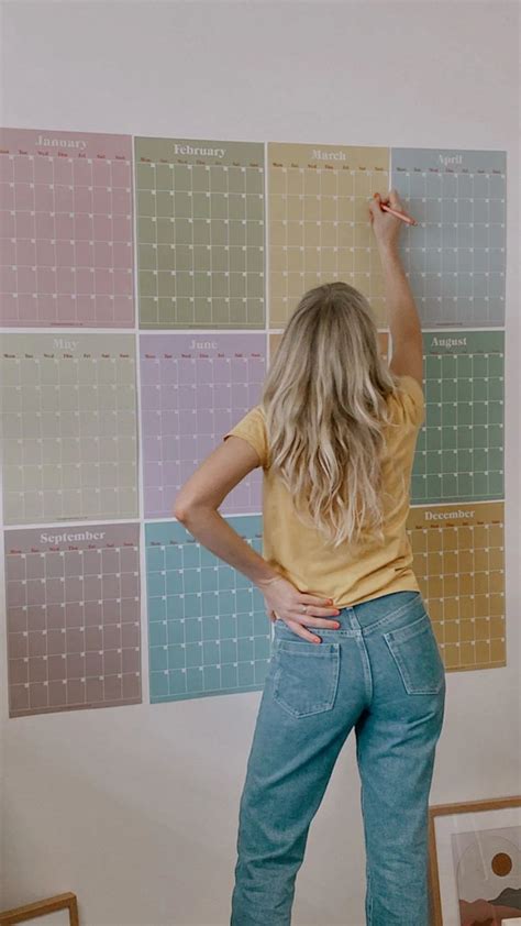 a woman standing in front of a wall with calendars on it's side