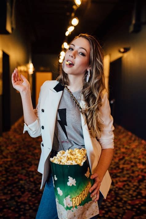 a woman holding a popcorn bucket and pointing at something