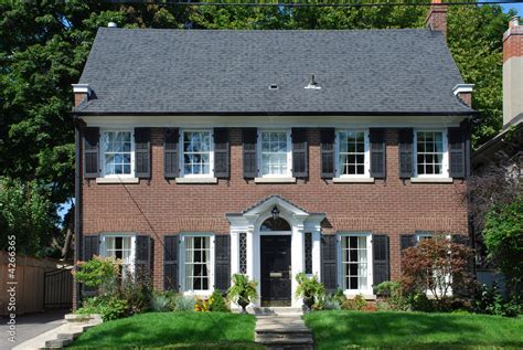 Two storey red brick house with black shutters Stock Photo | Adobe Stock