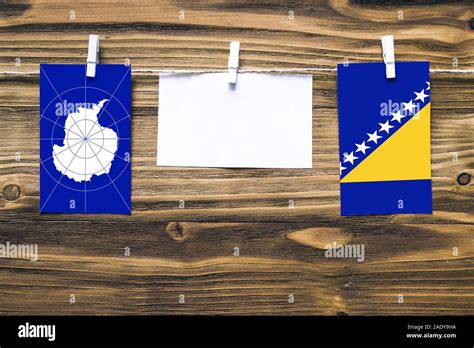 Hanging flags of Antarctica and Bosnia Herzegovina attached to rope with clothes pins with copy ...