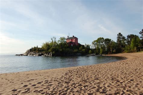 a house on an island in the middle of the ocean with footprints leading to it