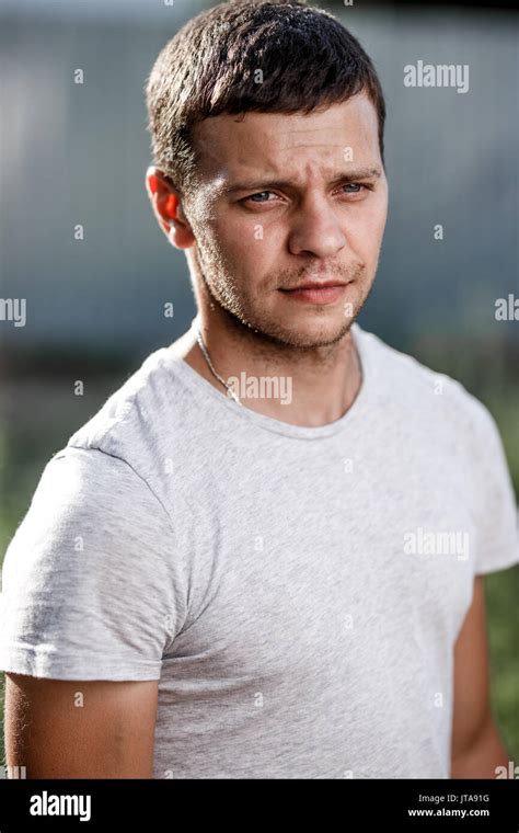 Outdoor portrait of a handsome young man in jeans and gray t-shirt ...