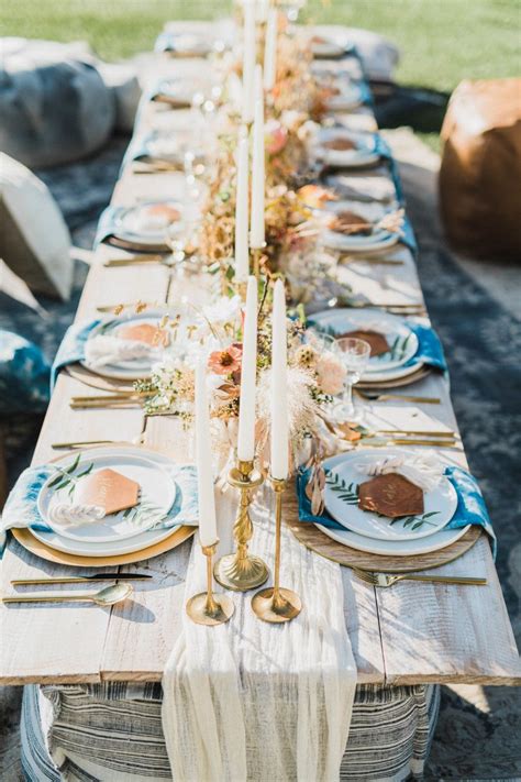 a long table set with plates and candles for an outdoor dinner party in the sun