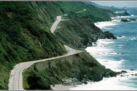 a scenic view of the ocean and coastline with a road going down it's side