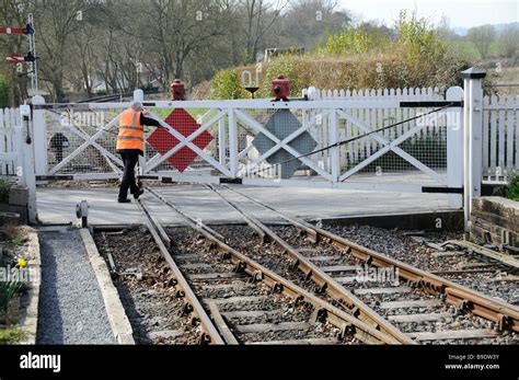 Railway worker pushing open level crossing gate of a unmanned crossing This one is at Tenterden ...