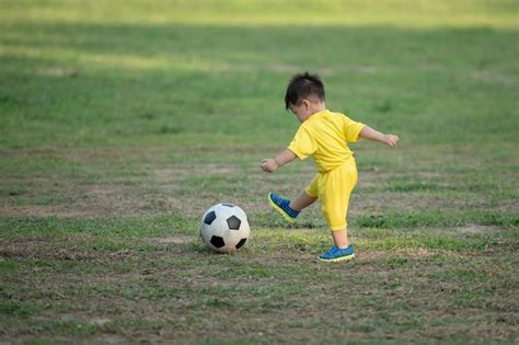 Premium Photo | Little boy playing football in the field.