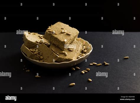 Sunflower halva with seeds on plate, on black background Stock Photo - Alamy