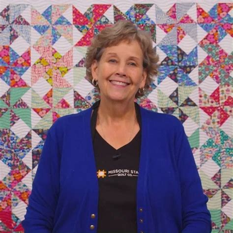 a woman standing in front of a quilt