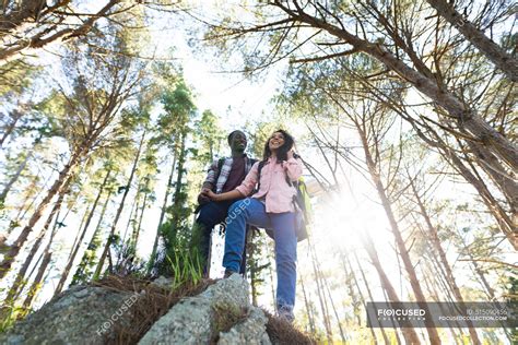 Happy diverse couple with backpacks hiking in countryside. healthy, active outdoor lifestyle and ...