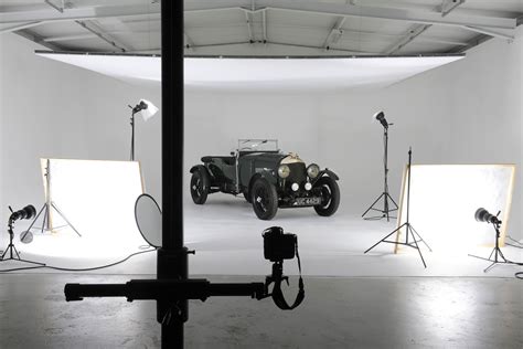 an old fashioned car is being photographed in front of two light stands and three photography ...