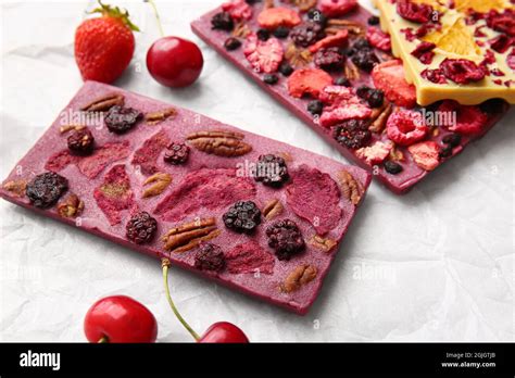 Handmade chocolate bars with fruits, berries and nuts on parchment ...