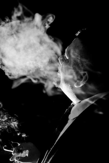 Premium Photo | Close-up of man in suit smoking cigar at night in black ...