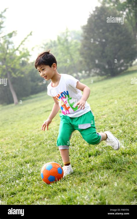 Boy playing football in field Stock Photo - Alamy