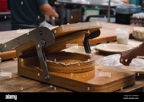 A wooden, hand-controlled pie crust press in a small, professional ...