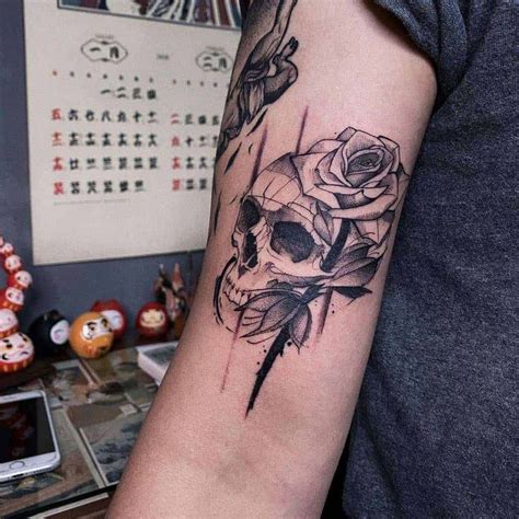 a skull and rose tattoo on the arm