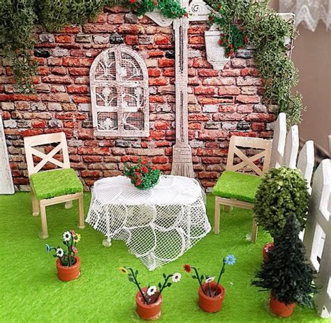 there is a miniature table and chairs set up in front of a brick wall with potted plants