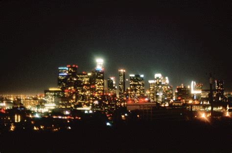 the city skyline is lit up at night with bright lights in the dark, as ...