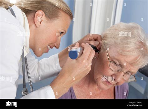 Ear examination. General practitioner using an otoscope to examine anelderly patient's ear Stock ...