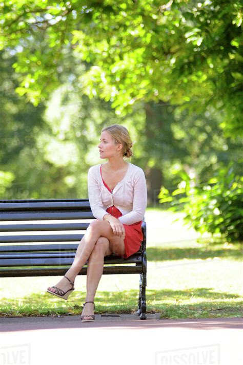 Young woman sitting on park bench - Stock Photo - Dissolve