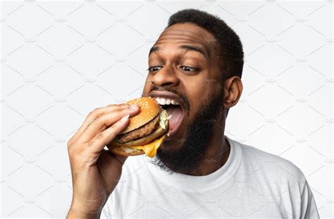 Portrait Of Hungry Black Man Eating Burger Over White Background | Stock Photos ~ Creative Market