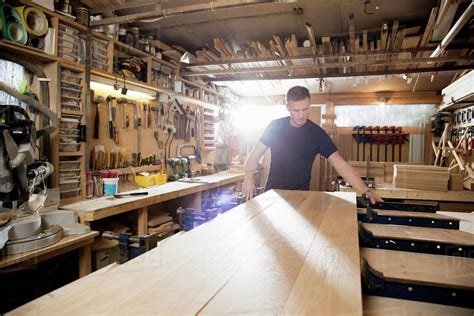 Craftsman preparing planks of wood in workshop - Stock Photo - Dissolve