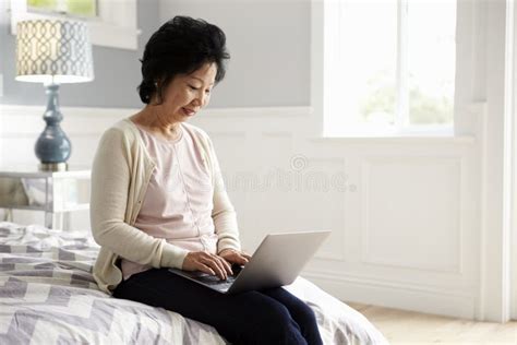 Senior Woman Sitting on Bed Using Laptop Computer Stock Photo - Image of home, laptop: 76286904