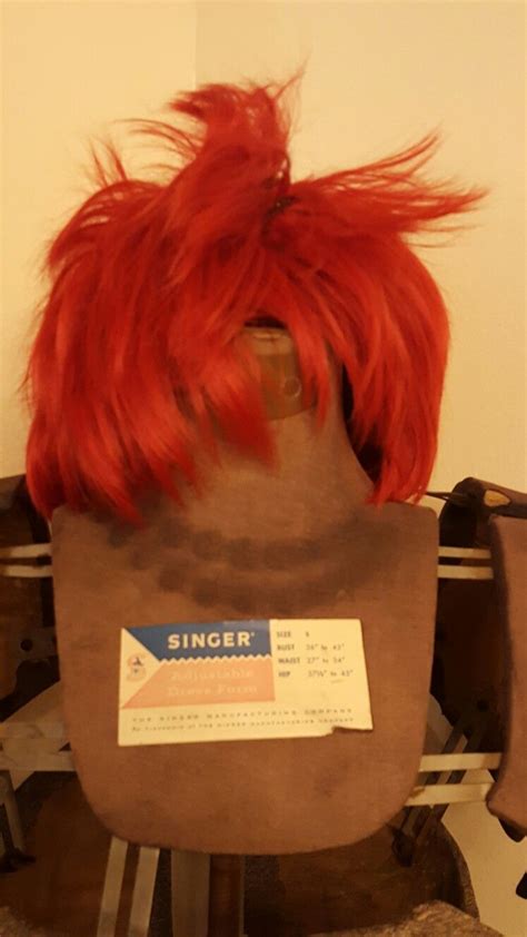 a wig with red hair sitting on top of a wooden chair next to a wall