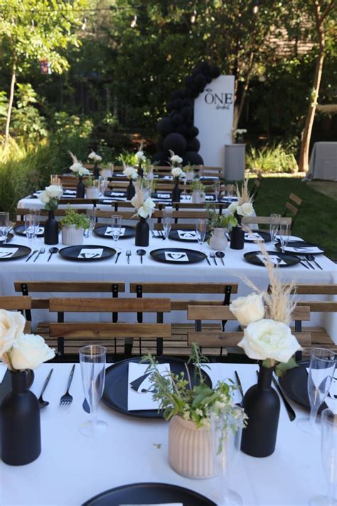 the table is set with black and white plates, napkins, and vases