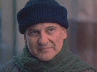 an older man wearing a green scarf and a black knitted hat is looking ...