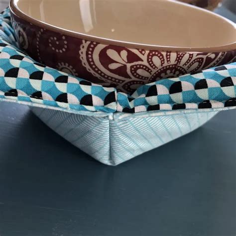 a blue and white bowl with a bow tie on it sitting on a table next to another bowl