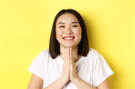 Premium Photo | Close up of cute asian woman saying thank you and smiling, holding hands in ...