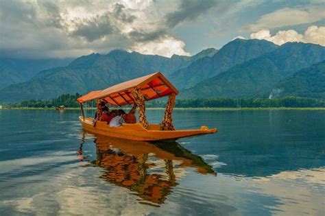 two people are in a small boat on the water with mountains in the back ground