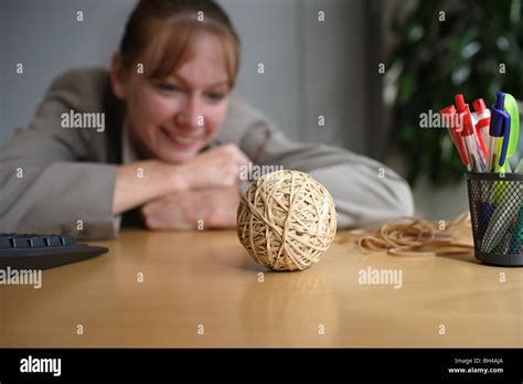 A businesswoman looking at a hand made rubber band ball on an office desk, smiling Stock Photo ...
