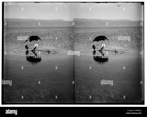Around the Dead Sea. Man floating with book and umbrella in hands Stock ...