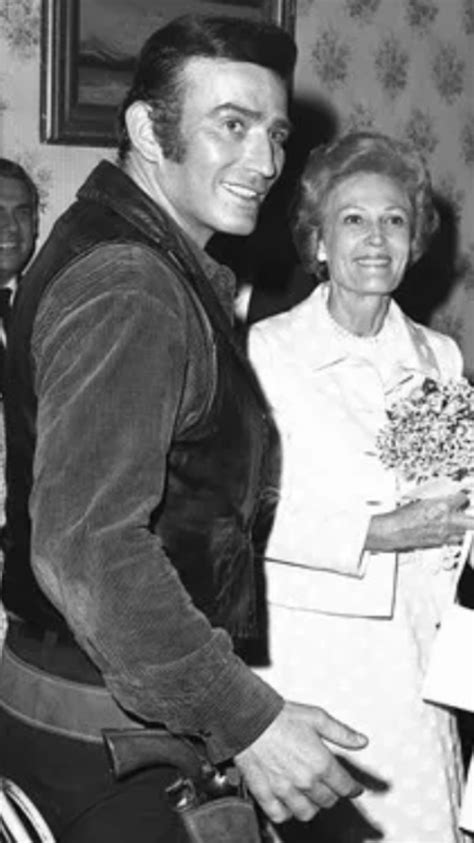 an old black and white photo of a man in a suit holding flowers with ...