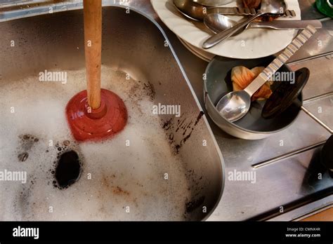 Blocked kitchen sink with plunger Stock Photo - Alamy