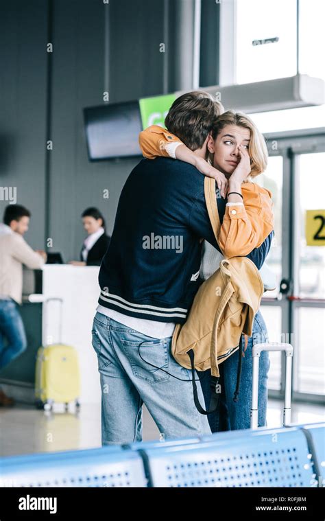 emotional young couple hugging and girl crying in airport terminal ...