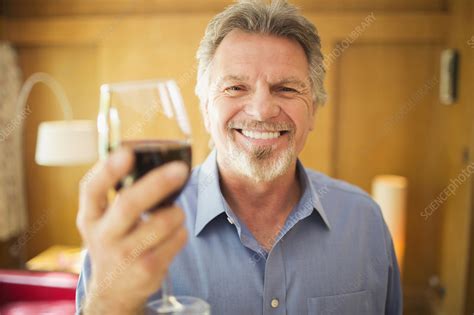 Carefree senior man drinking red wine - Stock Image - F032/2570 - Science Photo Library