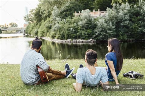 Three people relaxing in park with guitar — male, sitting - Stock Photo ...