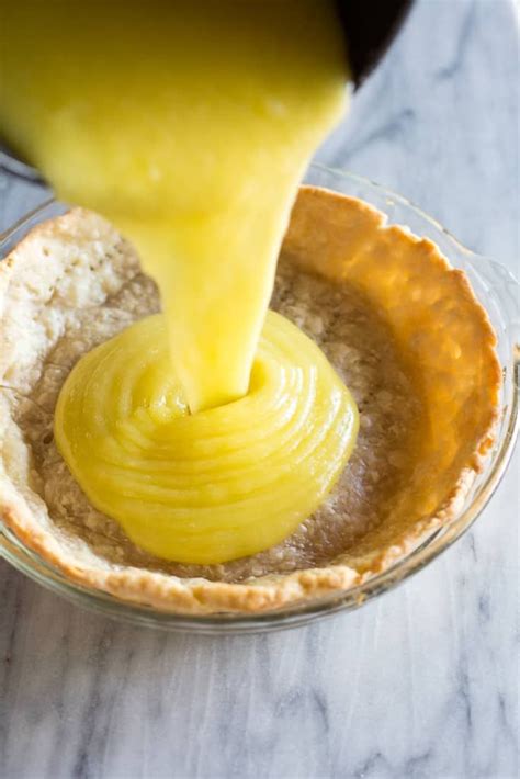 someone pouring sauce into a pie crust in a glass bowl