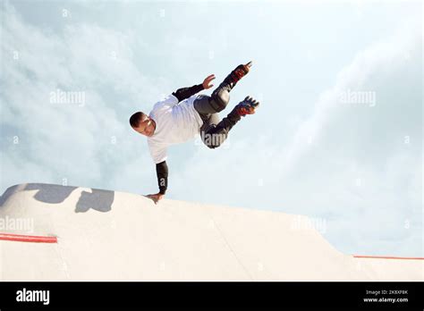 Energetic man on roller skates in motion at modern roller skate park. Roller skater doing ...