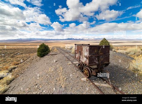 Old mining ore cart on tracks underneath a beautiful blue sky with clouds in the Nevada desert ...