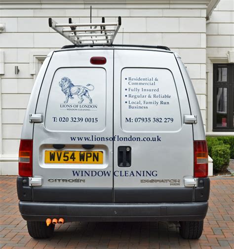 a van parked in front of a building with windows cleaning written on the back window