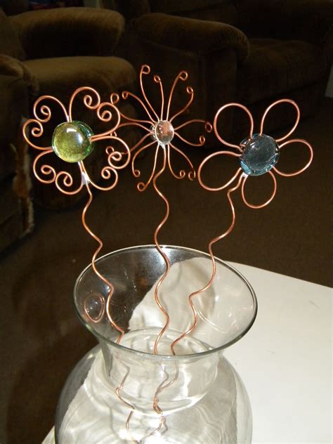 a glass vase filled with metal wire and flowers