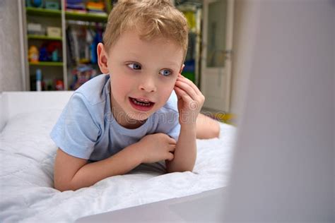 Little Blond Boy in Wireless Headphones Uses a Modern Laptop on the Bed Stock Image - Image of ...