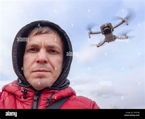 Man controls the flying drone. Grey drone with camera flying in the air outdoors. Little drone ...
