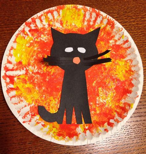 a paper plate with a black cat painted on it's face and flames in the background