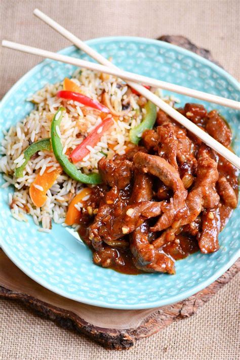 a blue plate topped with meat and rice next to chopsticks on a table