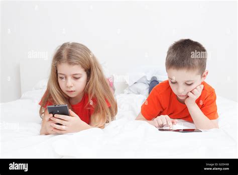 kids playing in bed with smart-phone Stock Photo - Alamy